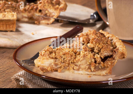Closeup of a slice of dutch apple pie with coffee mug and cut whole pie in background Stock Photo