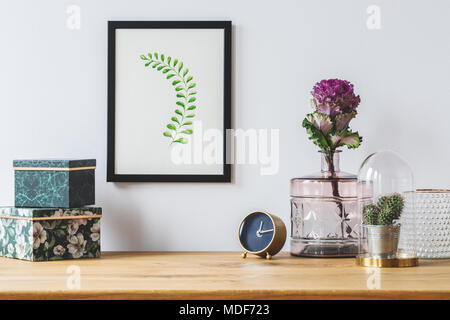 Close-up on floral style decorations on white background - green jewelry boxes, pink glass vase and simple, framed leaf artwork Stock Photo