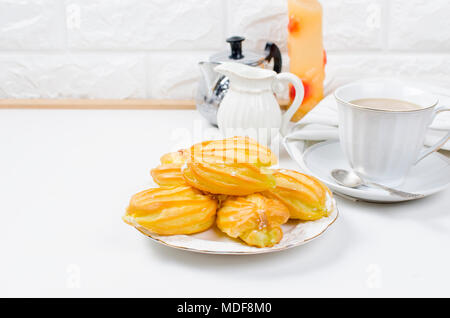 cup of strong coffee , eclairs and a jug with milk for breakfast on a white background. Serving. Top view, copy space Stock Photo