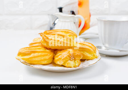 cup of strong coffee , eclairs and a jug with milk for breakfast on a white background. Serving. Top view, copy space Stock Photo