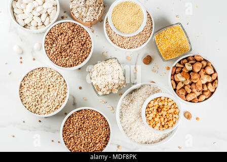 Selection various types cereal grains groats  in different bowl on white marble background, above Stock Photo