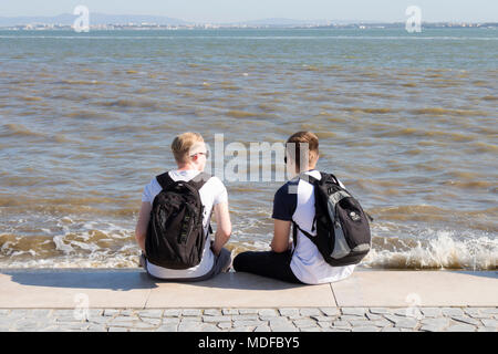 Young men sitting by the river Tagus. Lisbon, Portugal Stock Photo
