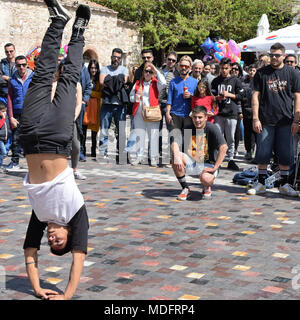 ATHENS, GREECE - APRIL 1, 2018: Man performing breakdance handstand move and crowd of people watching. Street dancing youth culture. Stock Photo