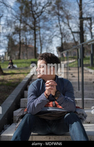 Man sitting on steps in public park Stock Photo