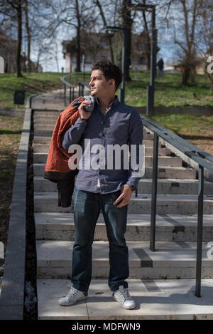 Man standing on steps with a jacket over his shoulder Stock Photo