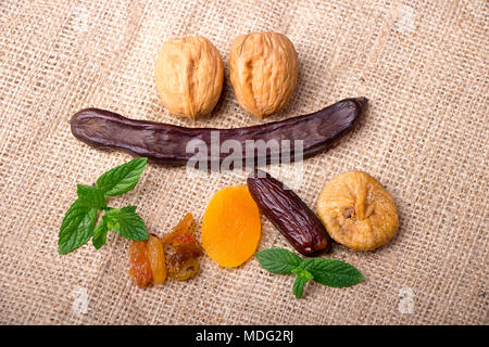 Mix of Ramadan Sweets - Dried fruits and nuts (dates, apricots, raisins, walnuts, and carob) on sackcloth background Stock Photo