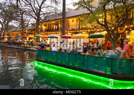 San Antonio River Walk -  - A tourist boat on the San Antonio river passing restaurants at dusk; the San Antonio Riverwalk, San Antonio Texas USA Stock Photo