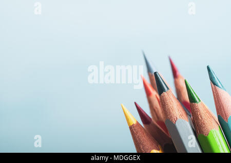 A selection of art pencils in different colours, grouped at lower right of frame with pale blue background providing copyspace to left and above. Stock Photo