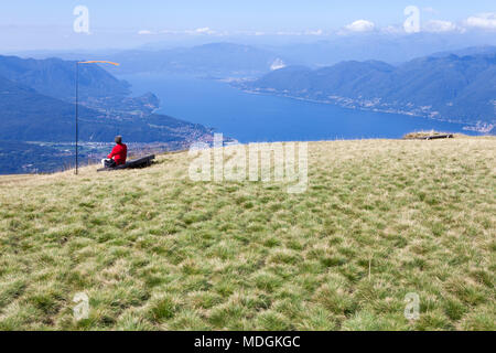 A tourist contemplating the beautiful view of Lago Maggiore (Lake Maggiore) from the top of Monte Lema (Mount Lema). Veddasca, Italy Stock Photo