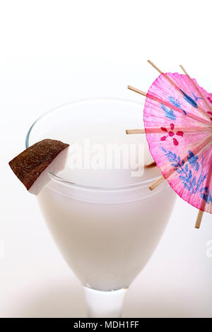 Glass of milk with a slice of coconut and a cocktail umbrella isolated on a white background Stock Photo