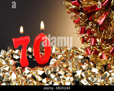 Birthday-anniversary candle showing Nr. 70  Lit red candle good for an anniversary or birthday background. Stock Photo