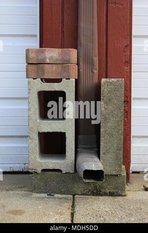 Homemade support for a drainage pipe made out of concrete blocks and brick. Stock Photo