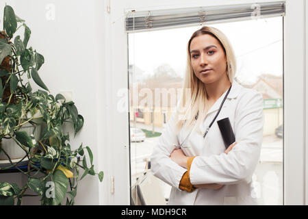 Confident smiling female doctor posing and looking at camera with arms crossed Stock Photo