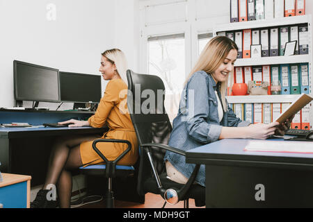 Cheerful women working with computers in the office. Two female accountants  working in office. Stock Photo