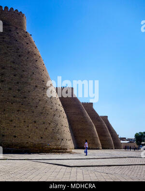 BUKHARA, UZBEKISTAN - APRIL 2015: A woman looks up at the enormous Ark fortress in the UNESCO-listed Historic Centre of Bukhara on the silk road in Uz Stock Photo