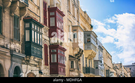 Malta, Valletta, traditional house building facade with sandstones and covered balconies, with blue sky background, perspective view Stock Photo
