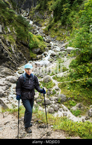 Female hiker on steep trail with rocky creek in the valley below; Grainau, Bavaria, Germany Stock Photo