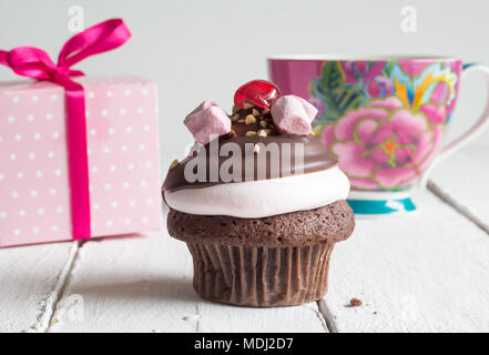 Cup cake birthday celebration background - Chocolate cupcake with pink gift box and teacup Stock Photo