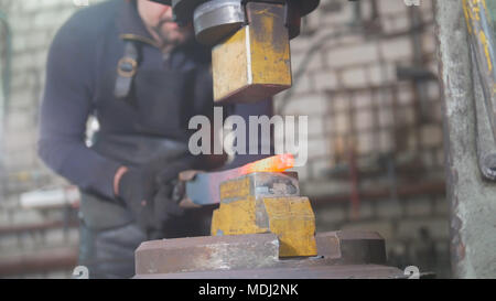 Automatic hammering - blacksmith forging red hot iron on anvil, extreme close-up Stock Photo