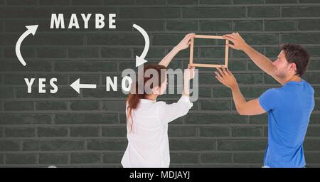 Couple holding picture frame against wall with Yes No Maybe text and arrows Stock Photo