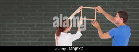 Couple holding picture frame against wall Stock Photo