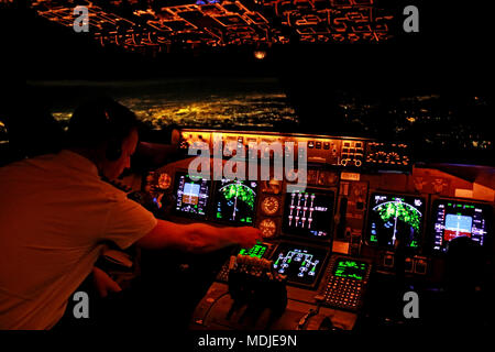 A pilot preparing the FMS on the flight deck of a Boeing 747-400 overhead NYC (in the background) for a landing at Atlanta Hartsfield-Jackson Stock Photo