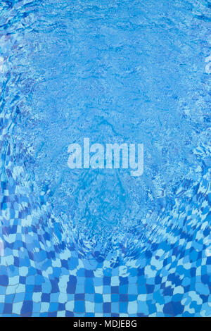 Abstract full frame background of rippled water and blue swimming pool mosaic tiles, viewed from above. Stock Photo