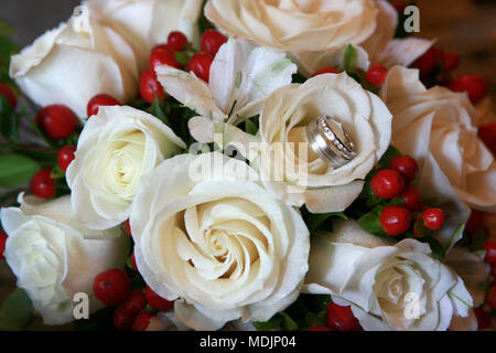 beautiful white roses wedding bouquet with the wedding rings in one flower Stock Photo