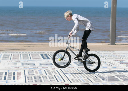 Young boy doing BMX stunts in Blackpool Lancashire. UK Weather. 20/04/2018.  Sunny start to the day on the Fylde Coast as holidaymakers enjoy he warm sunshine on the seafront promenade. Credit: MediaWorldImages/AlamyLiveNews Stock Photo