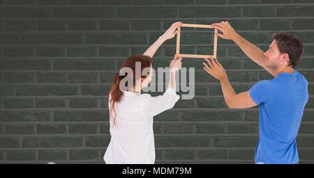 Couple holding picture frame against wall Stock Photo