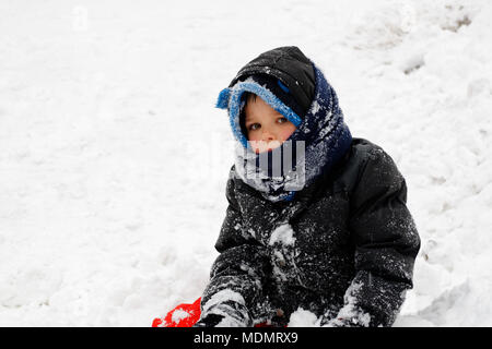A portrait of a young boy (5 yr old) dressed in outdoor winter clothes and covered in snow