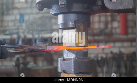 Blacksmith forging red hot iron on anvil - automatic hammering Stock Photo