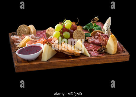 tasty plate of cheese, salami, prosciutto, grapes and pomegranate sauce Stock Photo