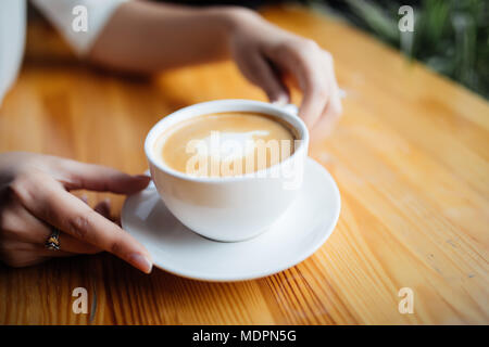 Close up of female hands holding cup of hot drink in cafeteria Stock Photo