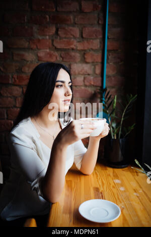 Young woman drinking coffee in a cafe outdoors.
