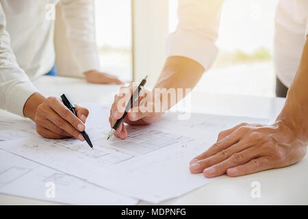 Engineers discuss a blueprint while checking information on a tablet computer in a office. Stock Photo