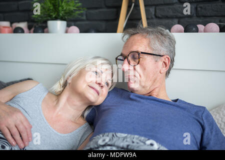 Portrait of happy senior couple lying together in bed Stock Photo