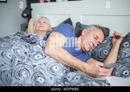 Portrait of senior man lying in bed using smartphone Stock Photo