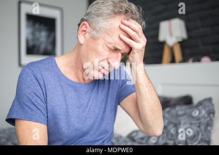 Portrait of senior man with migraine holding hand on forehead Stock Photo