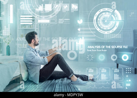 Calm translator sitting on the floor and switching channels Stock Photo