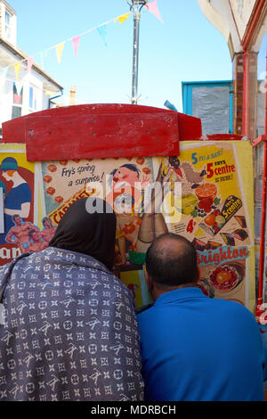 A Muslim couple having their picture taken using a comedy seaside cut out photo board - A captured moment on a summer day in Brighton England Stock Photo