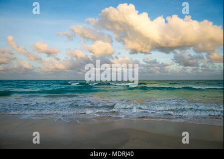 Waves of tropical turquoise sea crashing on the beach at dusk Stock Photo