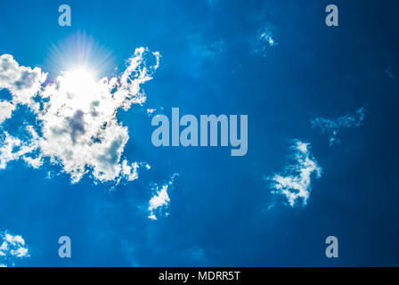 A Blue Sky with Sun, Sunbeams and Clouds. Stock Photo