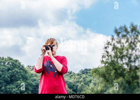 A teenage girl in a red T-shirt taking a photograph using an old Pentax Instamatic 35mm film camera Stock Photo