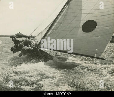 Skiff sailing on the Brisbane River. Location:  Brisbane, Queensland, Australia.  Date:  Undated.  Description: Every member of the crew is hanging overboard on this 18 foot skiff which is competing in the first championship heat on the Brisbane River. .   . Stock Photo