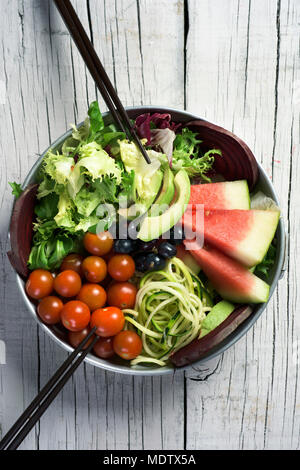 high angle view of an appetizing buddha bowl, made with avocado, cornsalad, lettuce, zucchini, blueberries, watermelon, beet and cherry tomatoes on a  Stock Photo