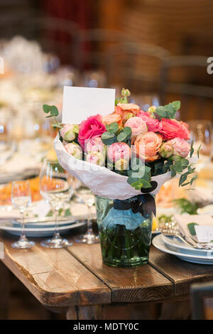 arrangement, interior decor, party concept. on the coner of old wooden table served for reception there is a wonderful bouquet composed of bright pink Stock Photo