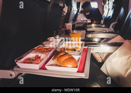 Tray of food. The passenger eats food on Board the plane on the background of the window. Meals on the plane. Different sets of food on the folding ta Stock Photo