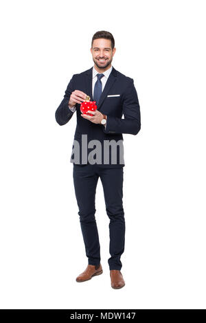 Young professional businessman drop bitcoin into red dotted piggy bank, isolated on white Stock Photo