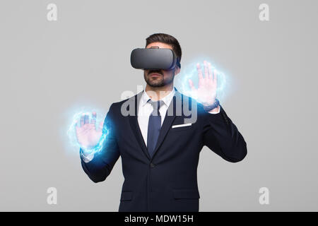 Young professional businessman in formal wear and VR headset touching imaginary interface Stock Photo